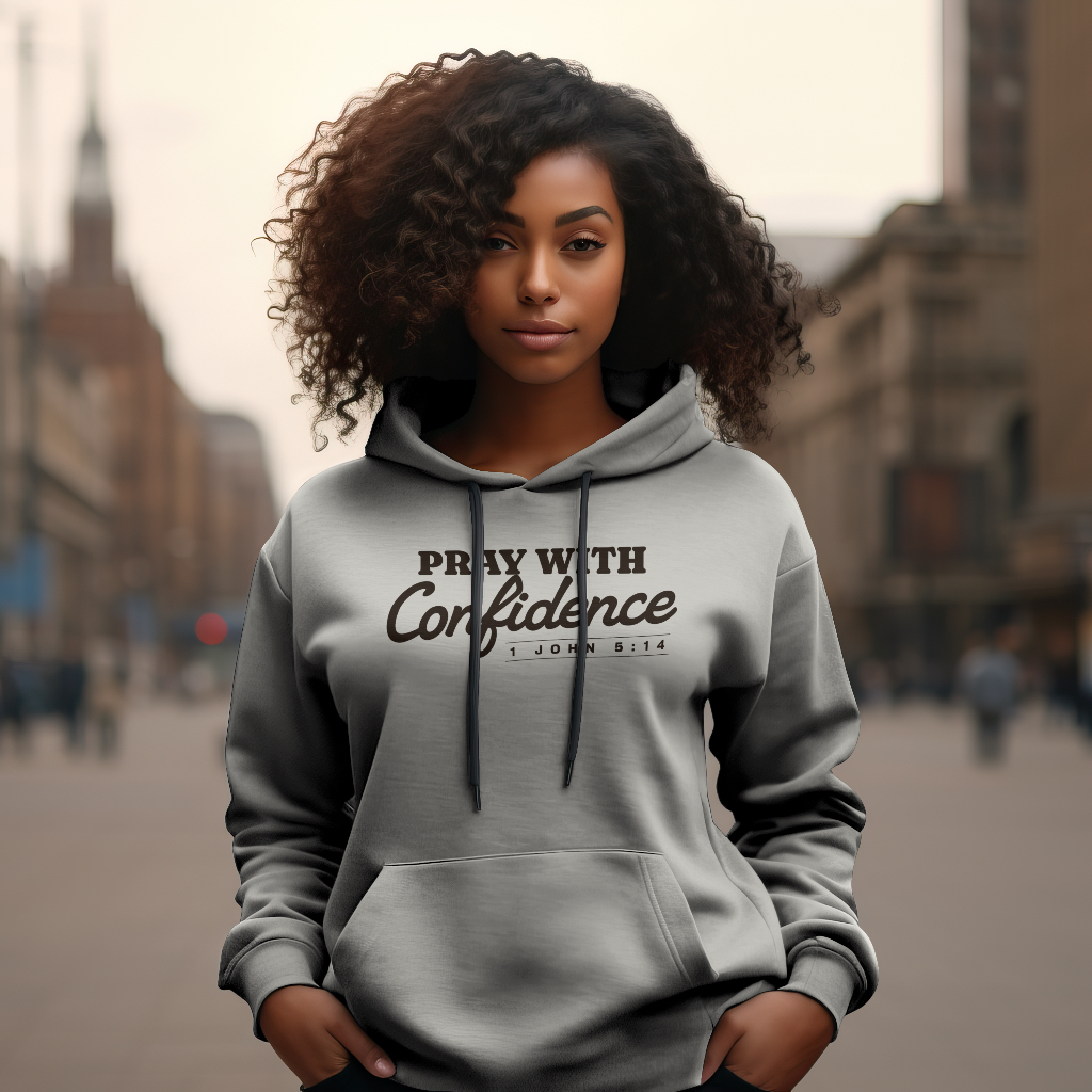 Black woman wearing a hooded sweatshirt with the words "Pray with Confidence" and 1 John 5:14 beneath it.